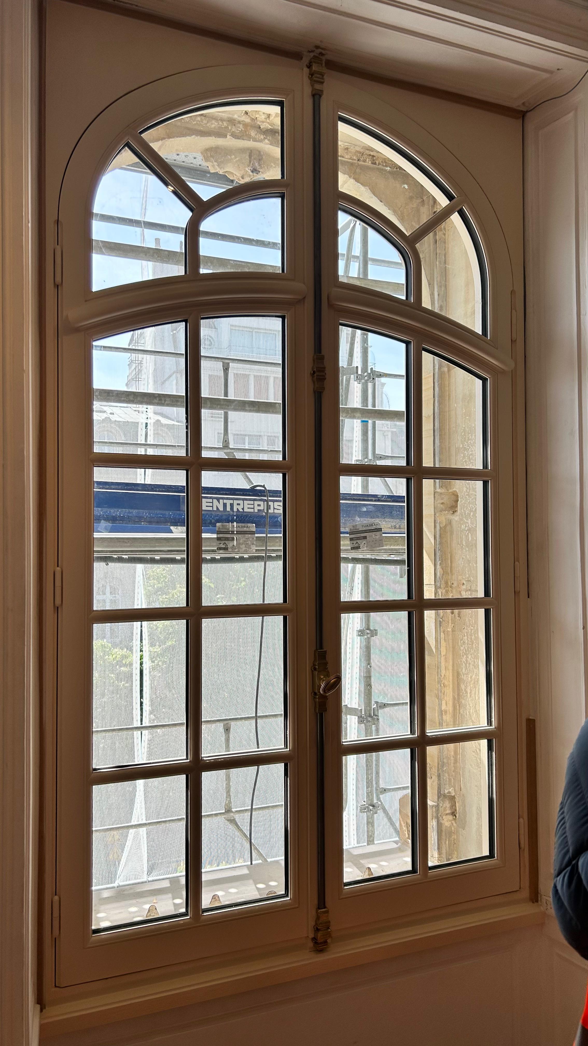 Menuiserie cintrée ouverte, façade sous échafaudage de ravalement.