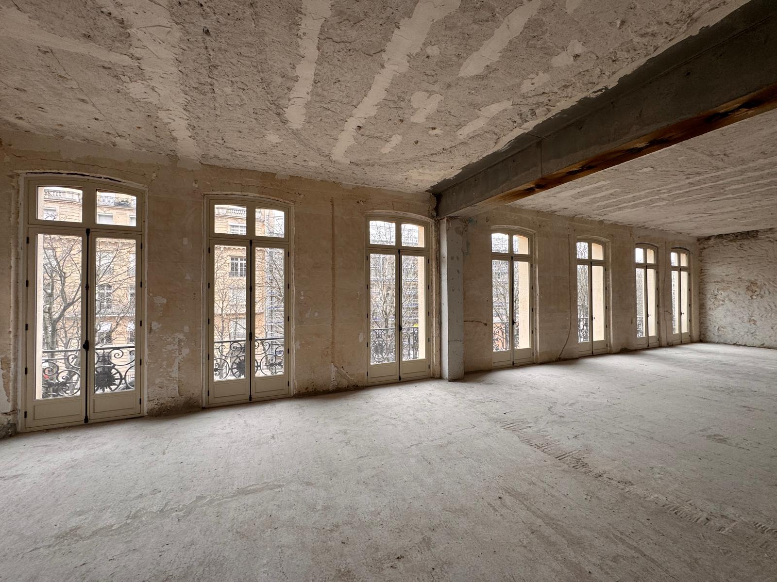 Vue intérieure : enfilade de fenêtres cintrées bois sur la rue parisienne.