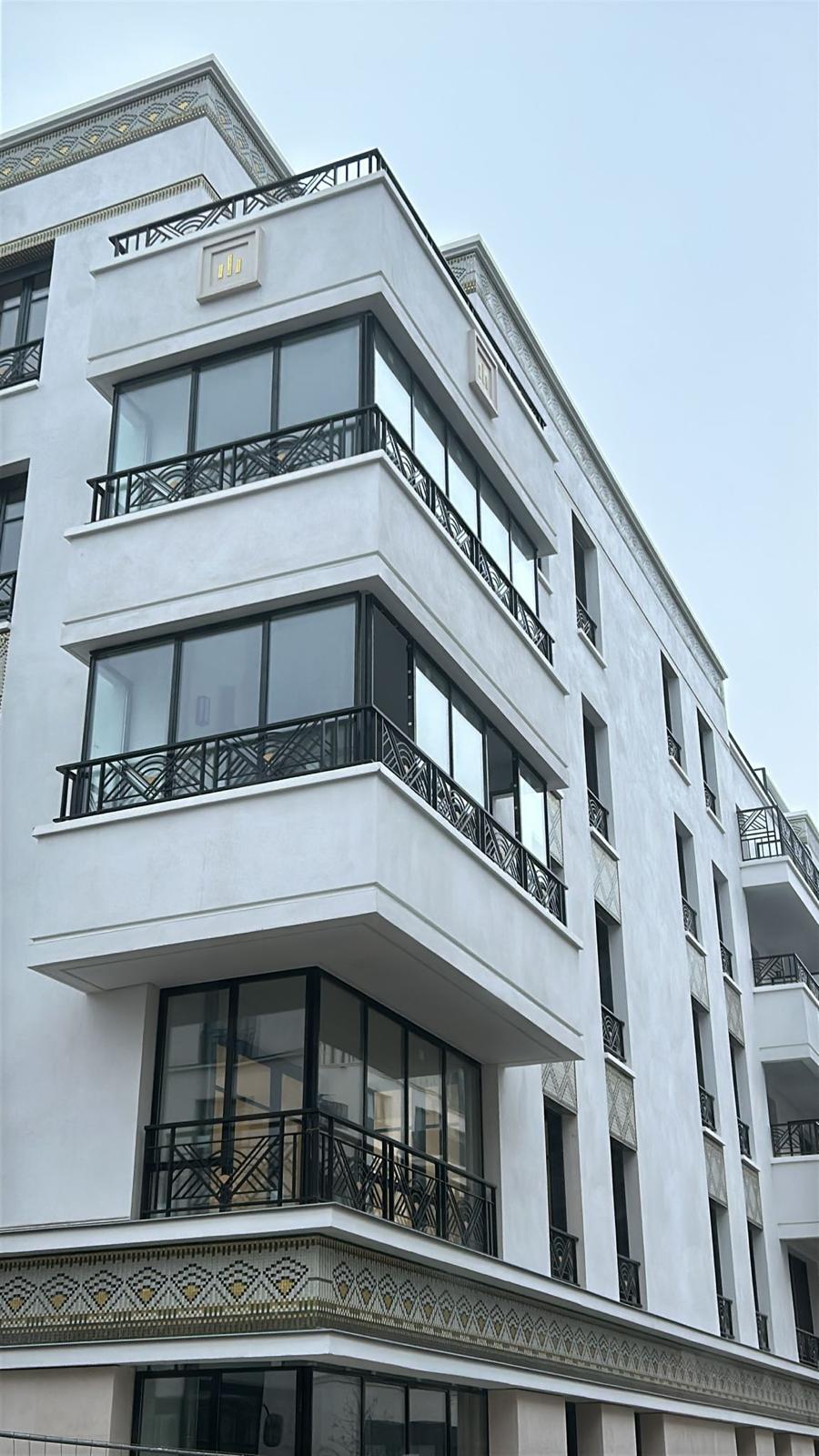 Façade pierre de taille et grandes baies vitrées toute hauteur.