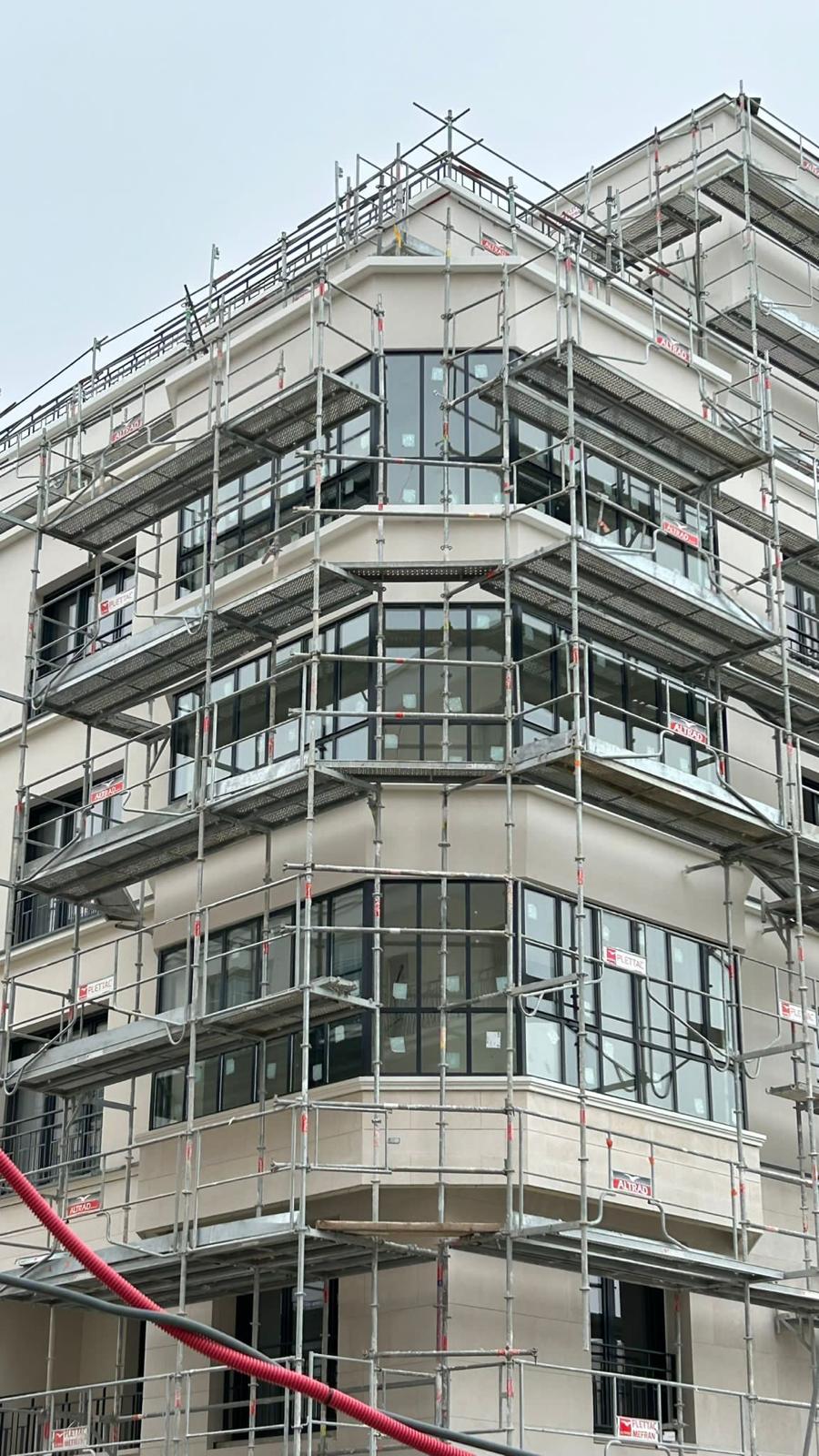 Pose des menuiseries en façade, immeuble sous échafaudage.
