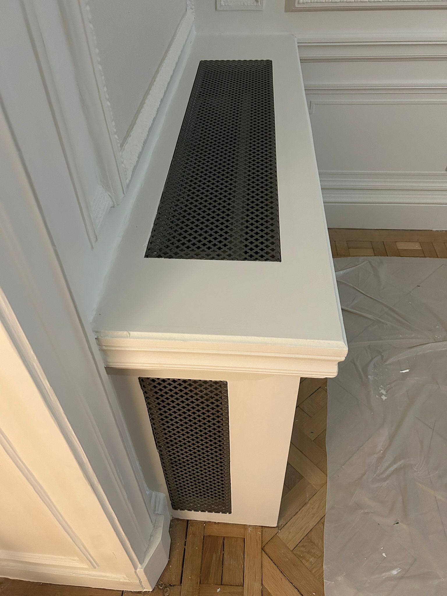 Détail du cache-radiateur à grille métallique, intégré aux moulures.