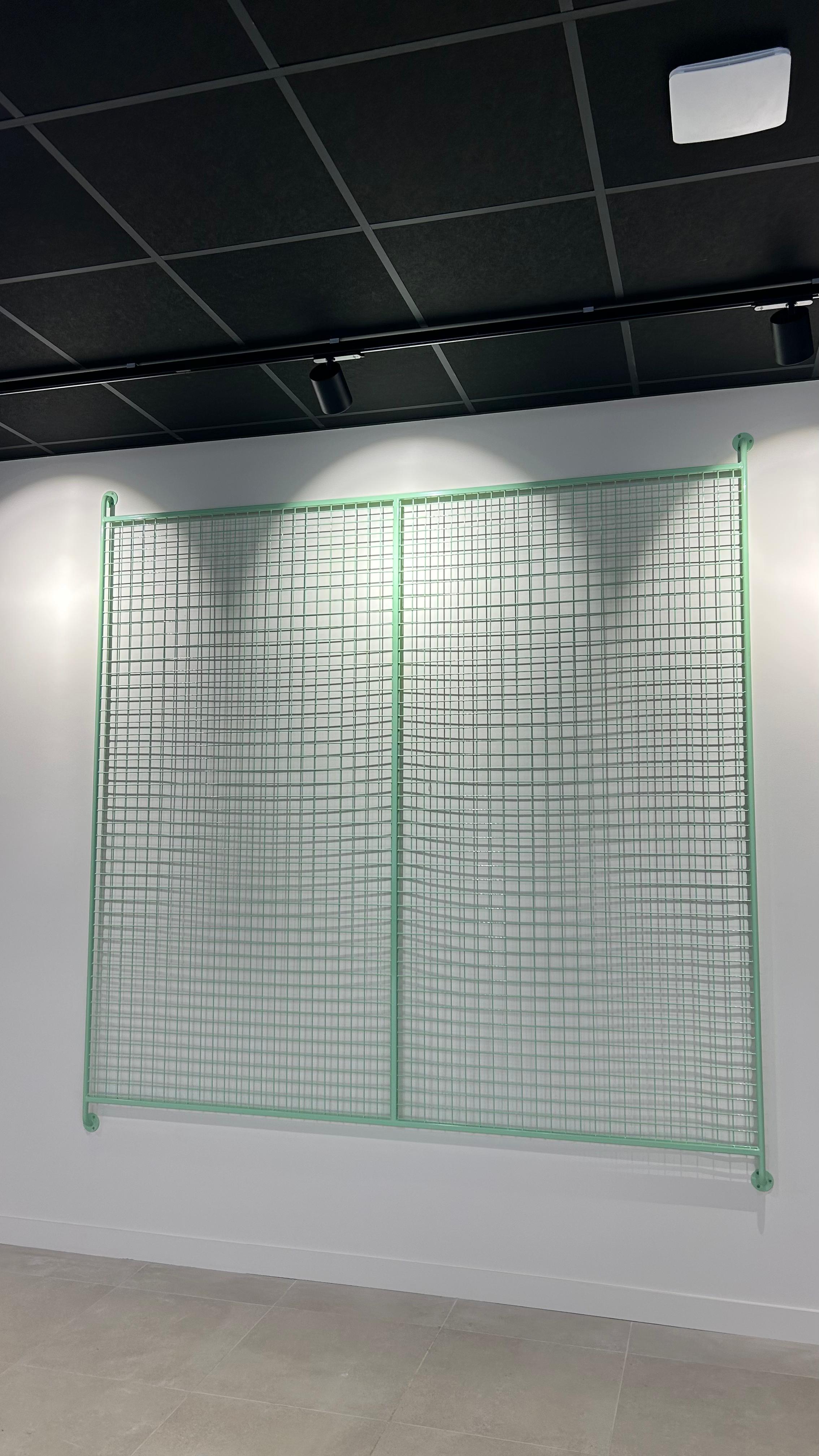 Grille métallique laquée en applique, habillage décoratif sur mesure de l'équipement technique.