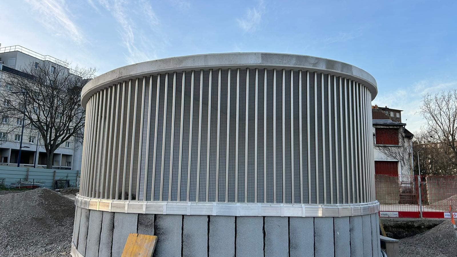 Émergence de ventilation habillée d'une résille de lames métalliques verticales.