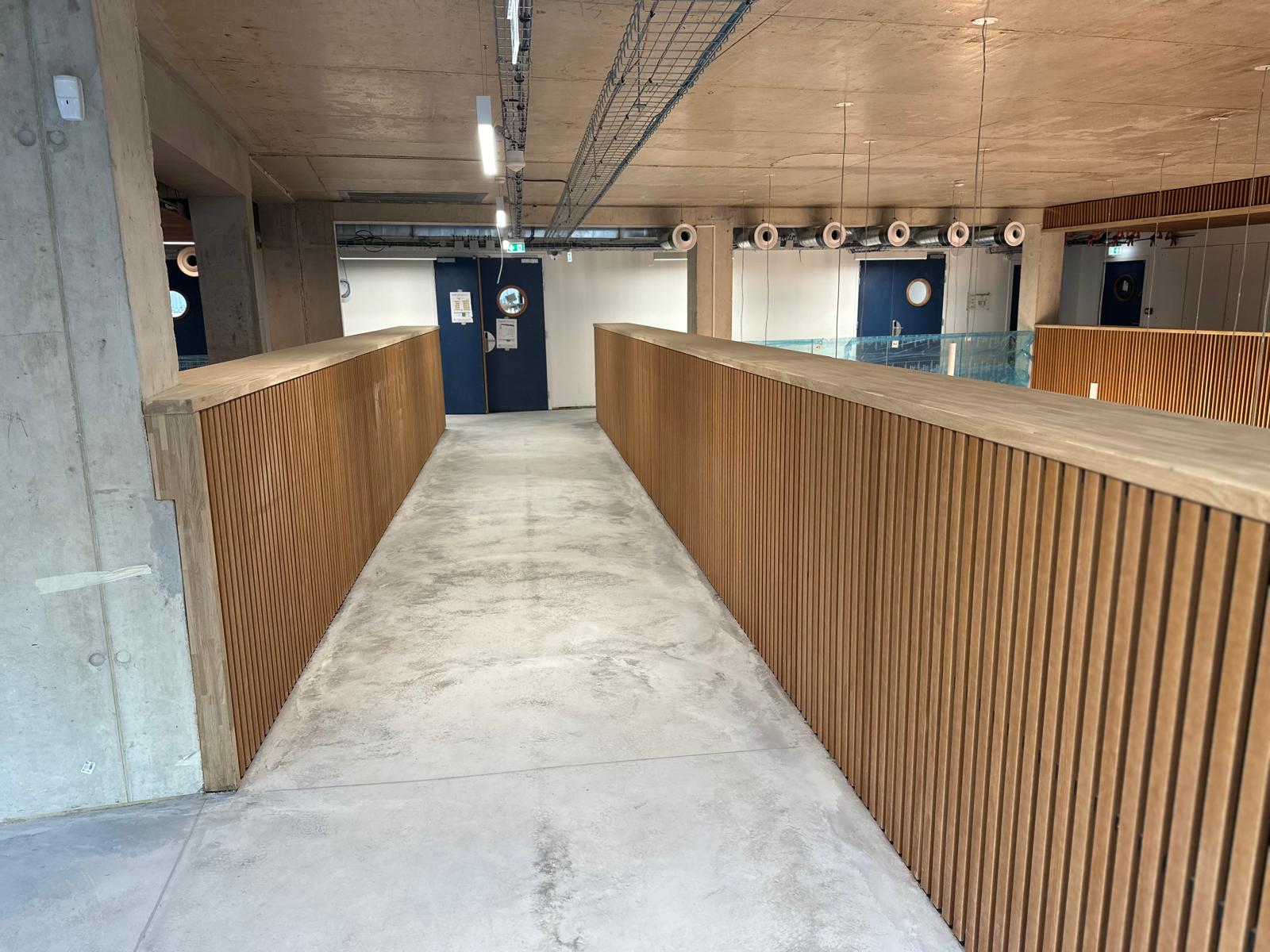 Rampe d'accès bordée de garde-corps habillés bois.