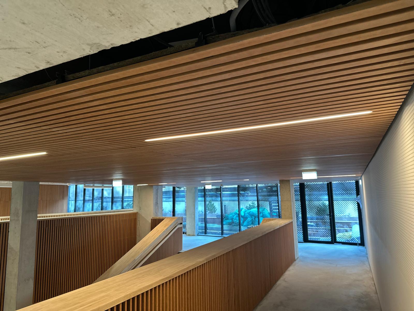 Faux-plafond à lames bois avec éclairage linéaire intégré.